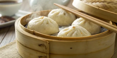 Steamed pork bao buns in a bamboo steamer.